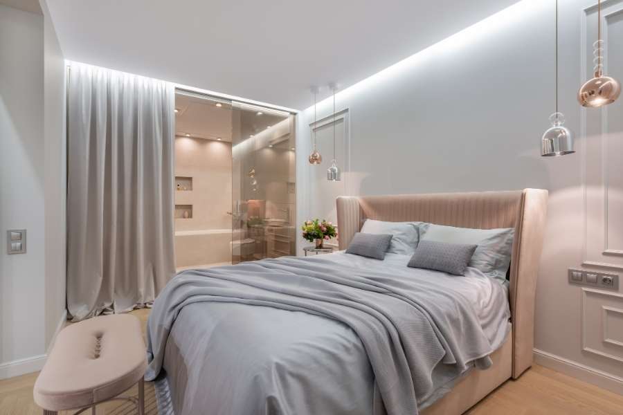 A modern bedroom featuring elegant hanging pendant lighting and a comfortable upholstered bed.