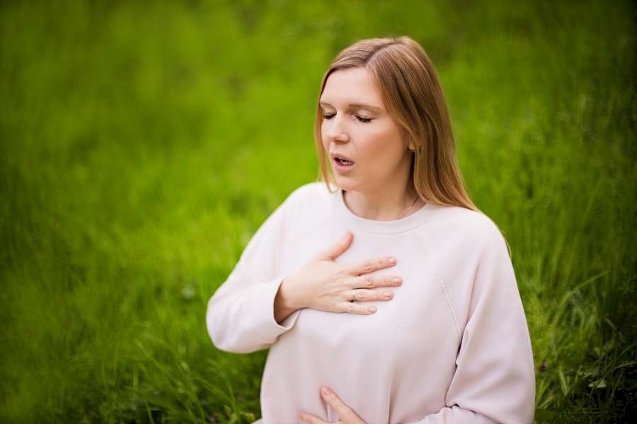 A woman practicing deep breathing outdoors to help lower your cortisol levels naturally.
