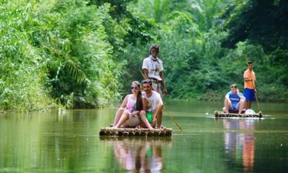 A couple enjoying a bamboo rafting tour along a lush jungle river during the best month to visit Khao Sok National Park.